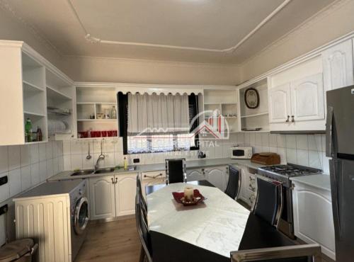 una cocina con armarios blancos y una mesa. en house for rent vlore en Vlorë