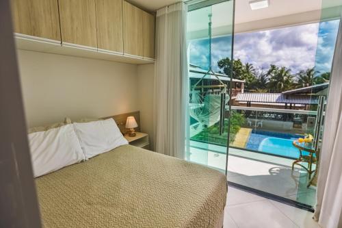 um quarto com uma cama e vista para uma piscina em Village Encantado em Guarajuba