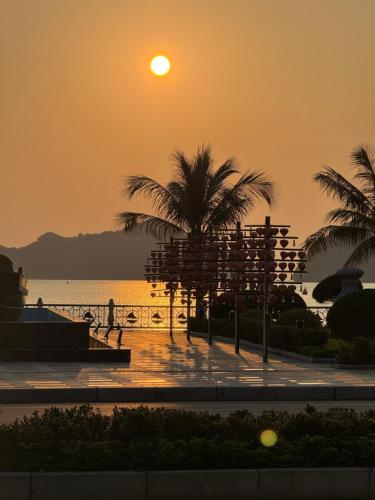 una puesta de sol sobre una playa con palmeras y el océano en Phoenix Flower Hotel en Cat Ba