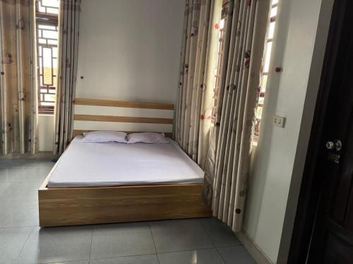 ein kleines Bett in einem Zimmer mit Fenstern in der Unterkunft Minh Tâm Hotel ( Nhà Nghỉ Minh Tâm ) in Vĩnh Phúc