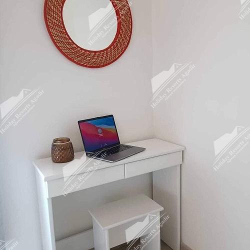 een laptop op een witte tafel met een spiegel bij Studio Taghazout Bay avec grand jardin in Taghazout