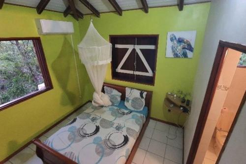 1 dormitorio pequeño con 1 cama en una pared verde en Au cœur de douenel bouillante cheques vacances acceptées, en Bouillante