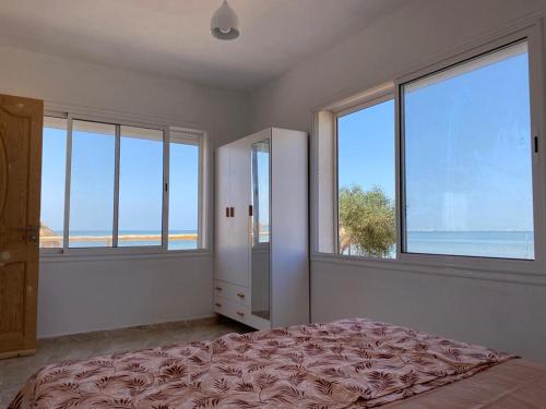 1 dormitorio con ventanas y 1 cama con vistas al océano en Beach houses Lost paradise en Mouamla