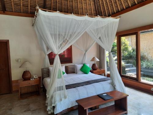 a bedroom with a bed with a mosquito net at Nefatari Exclusive Villas in Ubud