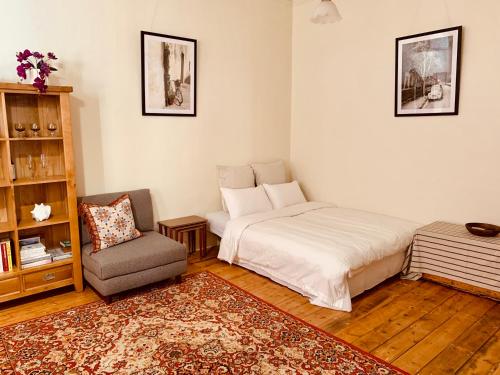 a bedroom with a bed and a chair at La Rouge Cottage in Bendigo
