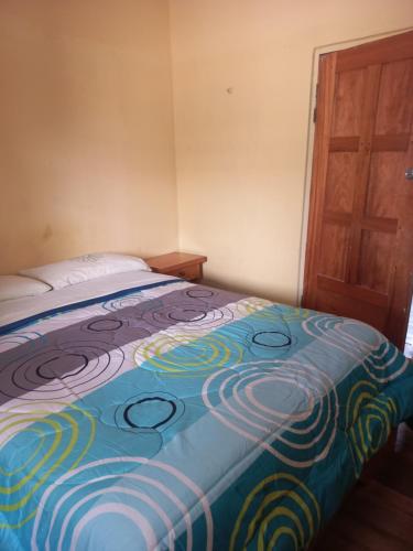 a bed in a room with a colorful blanket on it at Casa de Albert in Mindo