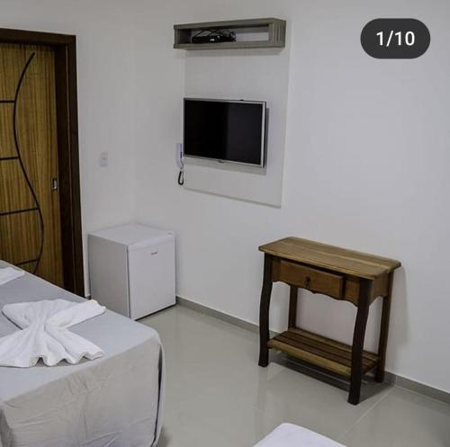 Habitación con cama, mesa y TV. en Pousada Família Eleutério en Penha