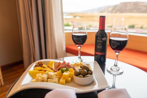 um prato de comida e dois copos de vinho em Lake Titicaca Hotel em Puno