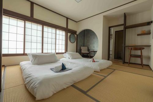 a large white bed in a room with windows at Himecho@Yasushi in Nozawa Onsen