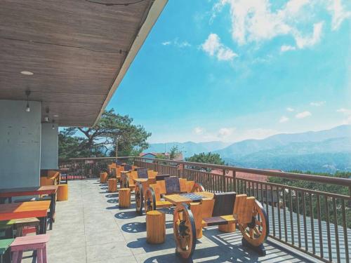 una fila de mesas y sillas de madera en un balcón en Evergreen Suites Cozy Baguio Loft Retreat, en Baguio