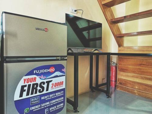 a refrigerator sitting next to a table with a box at Evergreen Suites Cozy Baguio Loft Retreat in Baguio