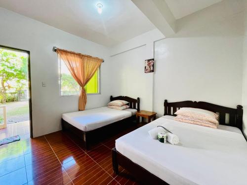 a bedroom with two beds and a window at FIESTA HAUS RESORT in Boracay