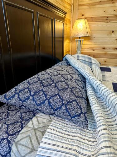 a bed with a blue and white comforter and a lamp at Mountain View Lodge & Cabins in Hill City