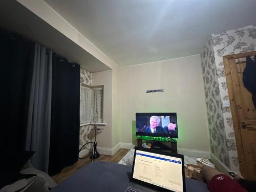 um quarto com um computador portátil em frente a uma televisão em For your care em Hornchurch