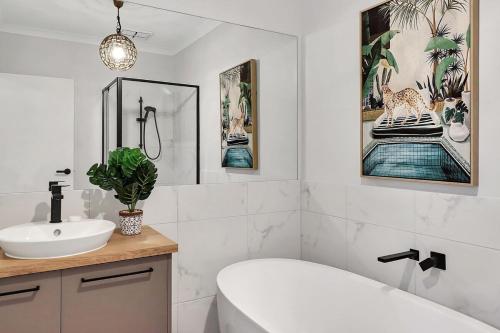 uma casa de banho com uma banheira branca e um lavatório. em Retreat on Bedajanawa em Geelong