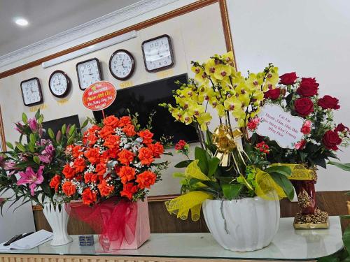 two vases filled with flowers on a table with clocks at Hoàng Gia Hotel Royal in Kim Bảng