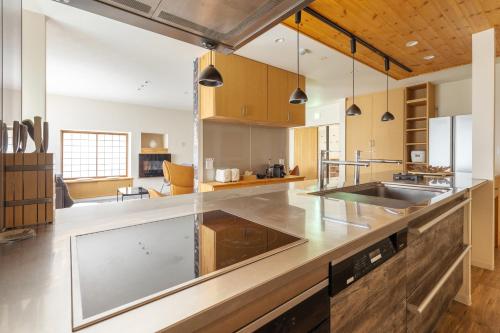 a kitchen with stainless steel countertops and wooden cabinets at Kawazen in Nozawa Onsen