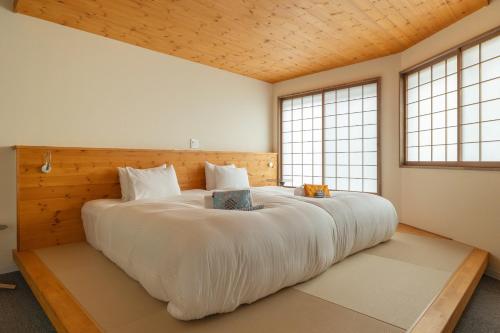 a large white bed in a room with windows at Kawazen in Nozawa Onsen