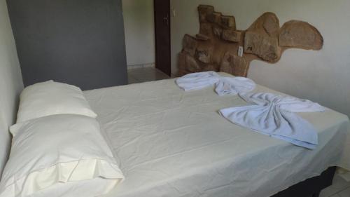 uma cama com lençóis brancos e uma cabeceira em madeira em Aurora suites chapada Diamantina em Lençóis