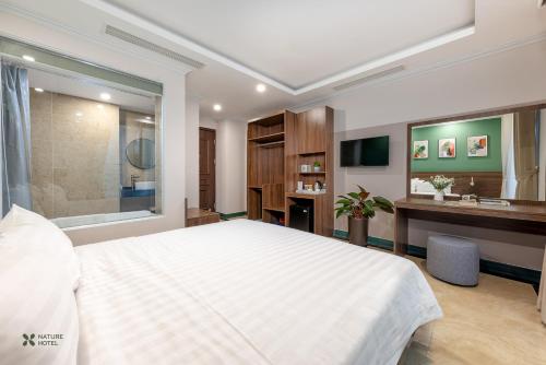a bedroom with a large white bed and a bathroom at Nature Hotel in Hanoi