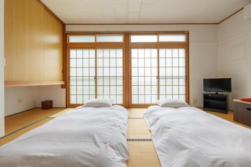 two beds in a room with a large window at Vaisala in Nozawa Onsen