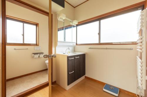 a bathroom with a sink and a toilet and windows at Vaisala in Nozawa Onsen