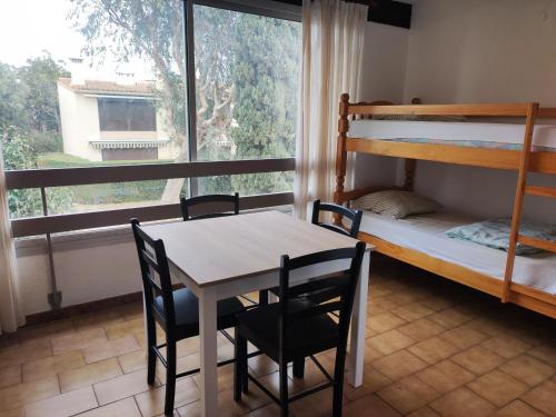 une chambre avec une table, des chaises et un lit superposé dans l'établissement Appartement avec Piscine, Tennis, et Parking - Proche Plages et Commerces - Idéal Familles - FR-1-776-70, à Argelès-sur-Mer