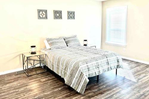 een witte slaapkamer met een bed met een gestreepte deken bij Renovated home 10 min from FLW! in Saint Robert