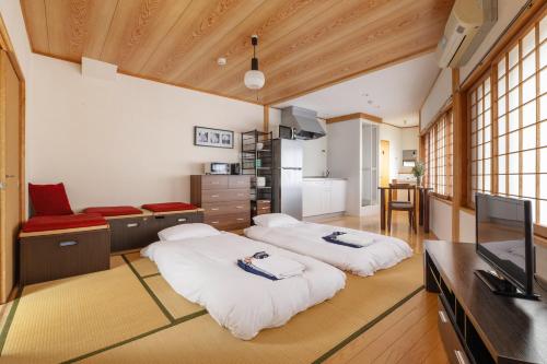 two beds in a room with a kitchen and a television at Corner House in Nozawa Onsen