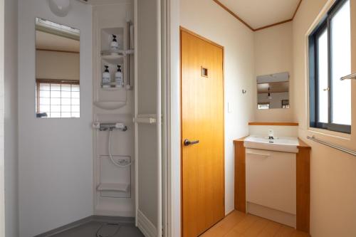 ein Bad mit einem Waschbecken, einem WC und einer Tür in der Unterkunft Corner House in Nozawa Onsen
