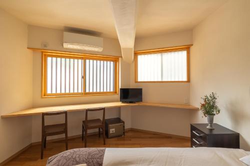 a bedroom with a desk and two windows at Corner House in Nozawa Onsen