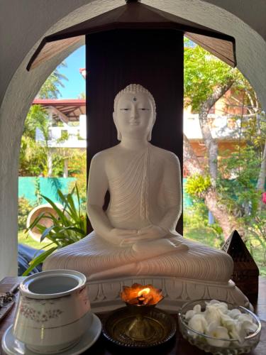 a statue of a buddha sitting on a table at Sri Villa Polwatta in Weligama