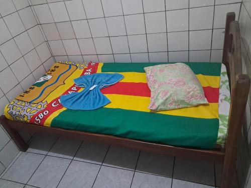 a small bed with a colorful blanket and pillows on it at Hotel pousada sonho meu in Arapiraca