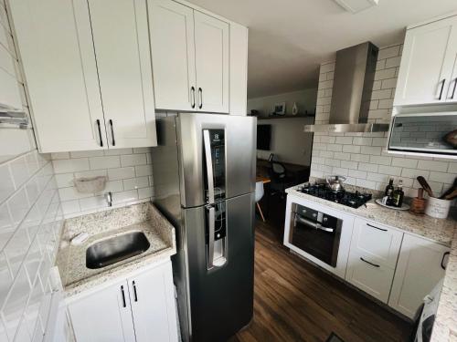 a kitchen with white cabinets and a stainless steel refrigerator at Refúgio Urbano - Asa Sul in Brasília