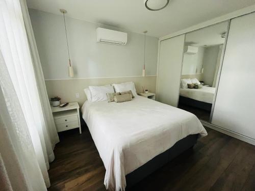 a bedroom with a large white bed and a mirror at Refúgio Urbano - Asa Sul in Brasília