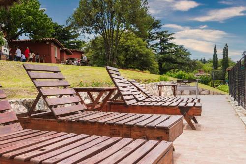 a group of wooden chairs and tables in a park at Castelar - Hotel & Apart in Huerta Grande