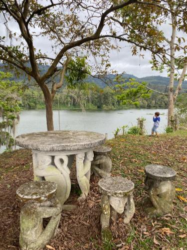 una mesa de piedra y sillas frente a un lago en Jicote finca de ecoturismo, en Cartago