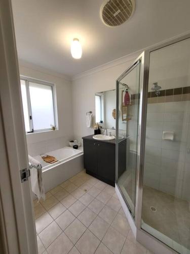 a bathroom with a shower and a tub and a sink at Villa Cinta @Cape View Resort in Broadwater