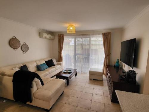 a living room with a couch and a tv at Villa Cinta @Cape View Resort in Broadwater