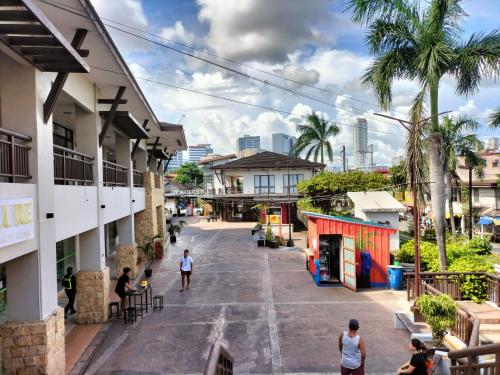 a group of people walking around a street with buildings at Cozy Staycation The Persimmon Studios in Cebu City