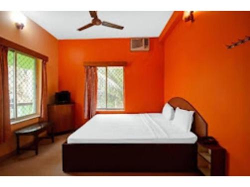 a bedroom with an orange wall with a bed in it at Goroomgo Indranil Digha in Digha