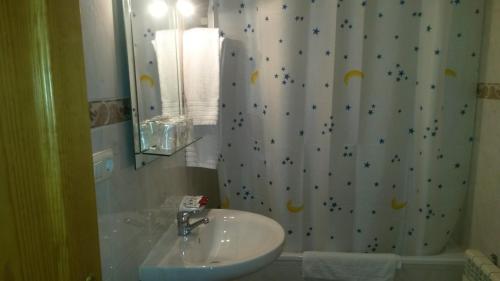 a bathroom with a sink and a shower curtain at Hostal Residencia Taray in Segovia