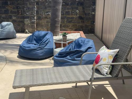 a bench with blue covers on a patio with a table at Evies White House Oasis I Pool & Close to Airport in Melbourne