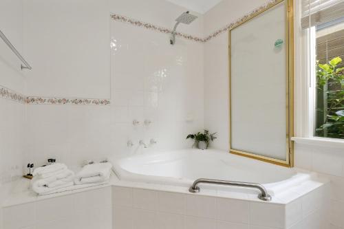 a white bathroom with a tub and a window at Mt.Martha Guesthouse By The Sea in Mount Martha
