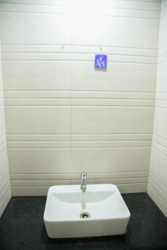 a white sink in a bathroom with a blue sign on the wall at Hotel Sachidanand-Walkable distance from Temple in Shirdi