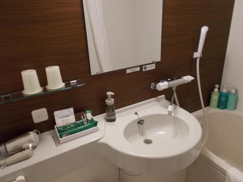 a bathroom with a white sink and a mirror at Hotel Route-Inn Katori Sawara Ekimae in Katori