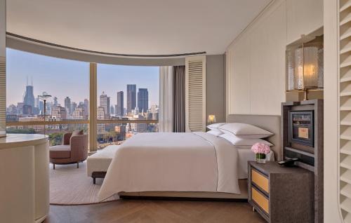 a bedroom with a bed and a view of a city at Regent Shanghai on the Bund in Shanghai