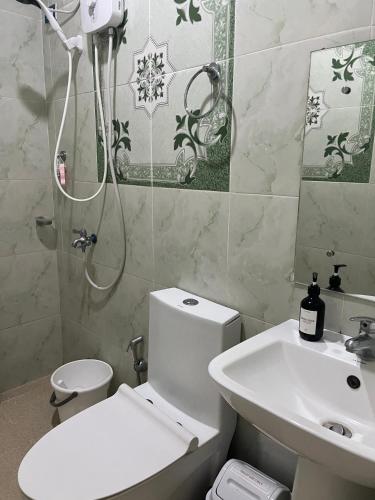 a bathroom with a toilet and a sink and a shower at Almar Apartelle in Oroquieta