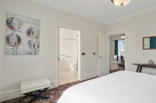 a white bedroom with a bed and a bathroom at Mt.Martha Guesthouse By The Sea in Mount Martha