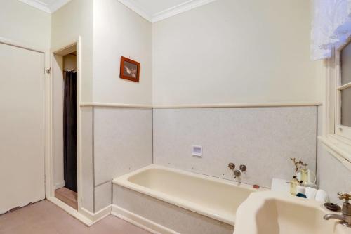 a white bathroom with a tub and a sink at GATSBY walk to Geelong CBD and Waterfront in Geelong